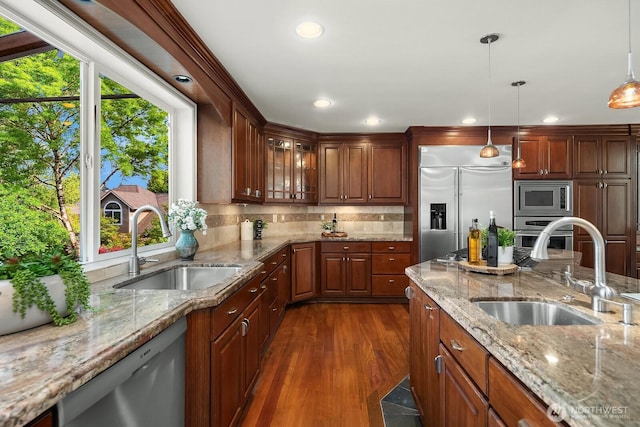 kitchen featuring a sink, built in appliances, recessed lighting, glass insert cabinets, and decorative light fixtures