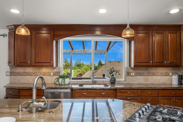 kitchen with a sink, hanging light fixtures, backsplash, dark stone counters, and recessed lighting