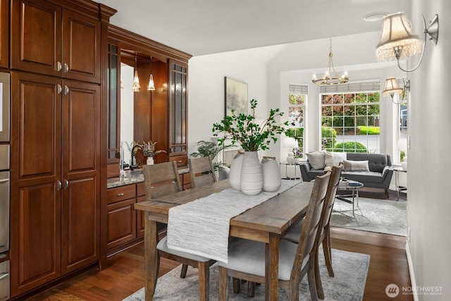 dining area with dark wood-style floors, a chandelier, and vaulted ceiling