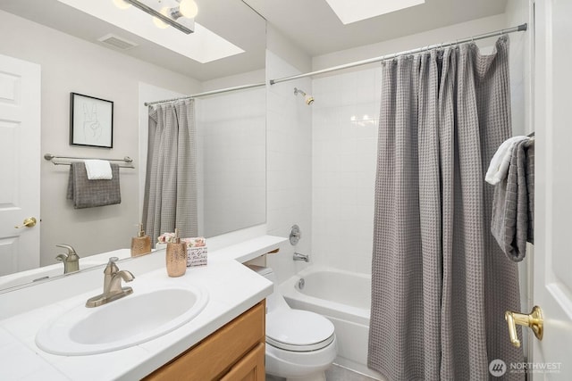 full bathroom with shower / bath combination with curtain, a skylight, toilet, and vanity
