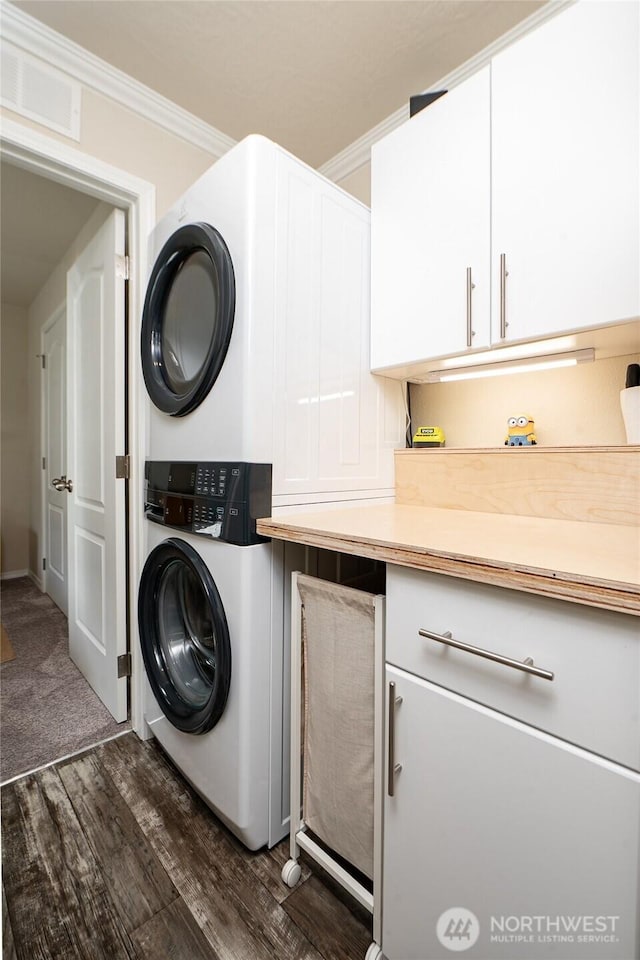 1200 Lincoln St Unit 121, Bellingham, WA 98229 - laundry room with stacked washer / drying machine, cabinet space, crown molding, and dark wood-style flooring