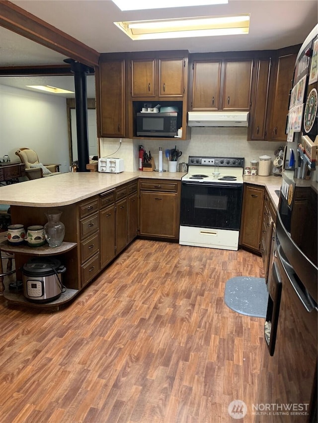 111 3rd St, Port Hadlock, WA 98339 - kitchen featuring electric range, stainless steel microwave, under cabinet range hood, light countertops, and open shelves