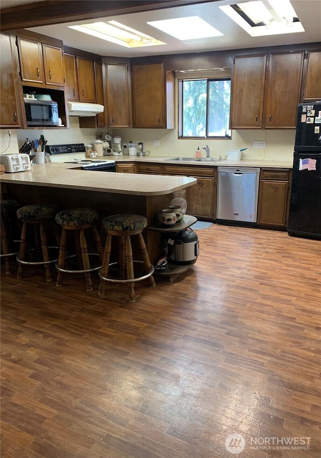 111 3rd St, Port Hadlock, WA 98339 - kitchen with appliances with stainless steel finishes, a peninsula, dark wood finished floors, and a kitchen bar