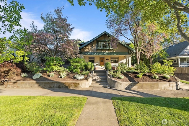 view of front facade featuring covered porch, stairway, and a front lawn