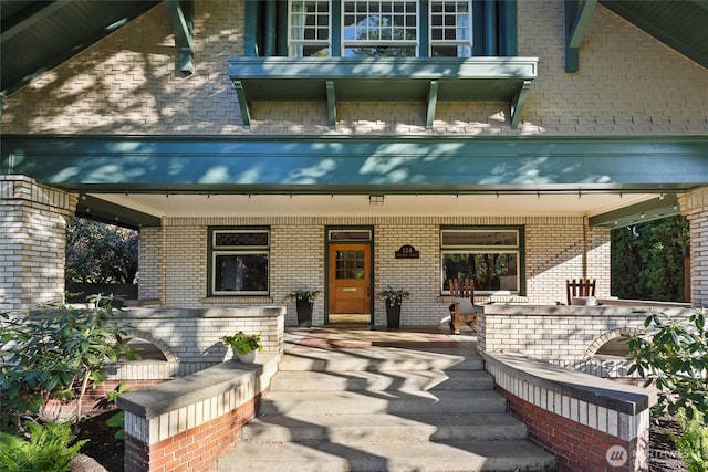property entrance featuring covered porch and brick siding