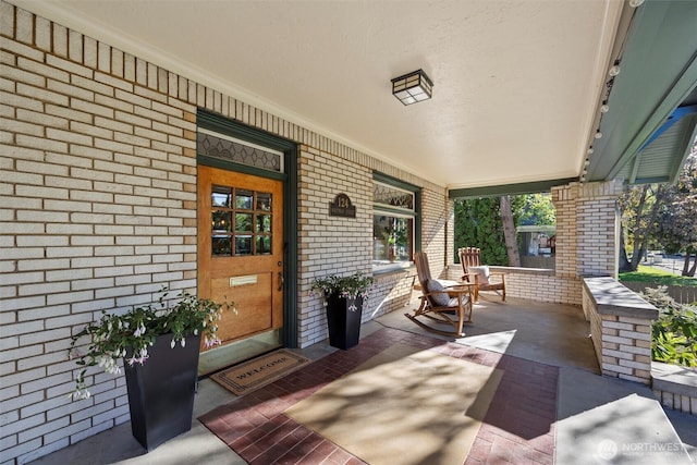 property entrance featuring covered porch and brick siding