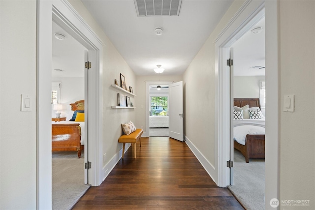 hallway featuring dark wood finished floors, baseboards, and dark carpet
