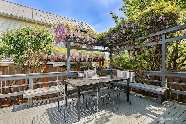 wooden terrace with outdoor dining area and fence