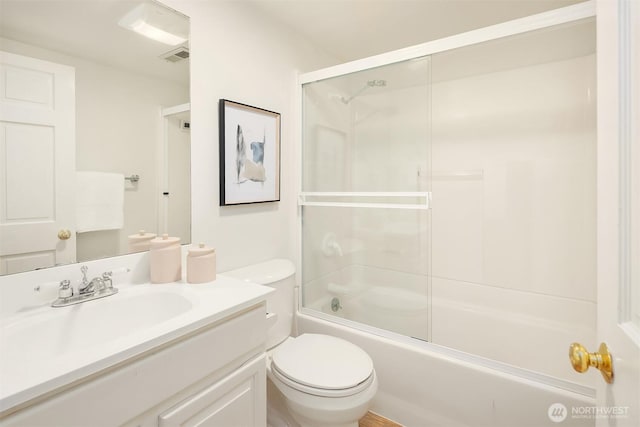bathroom with toilet, vanity, and combined bath / shower with glass door