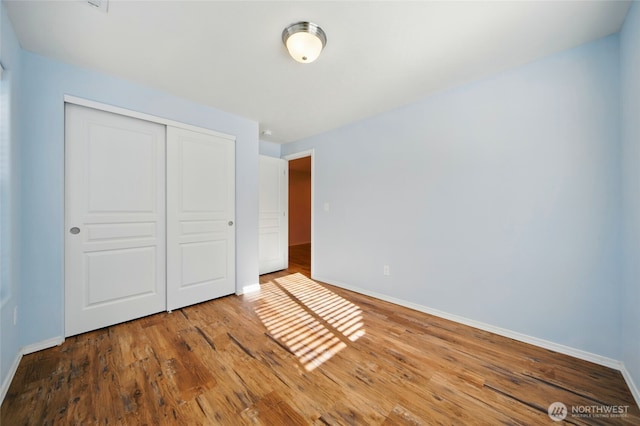 unfurnished bedroom with baseboards, a closet, and wood finished floors