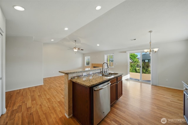 kitchen featuring dishwasher, a sink, light wood-style floors, a chandelier, and a center island with sink
