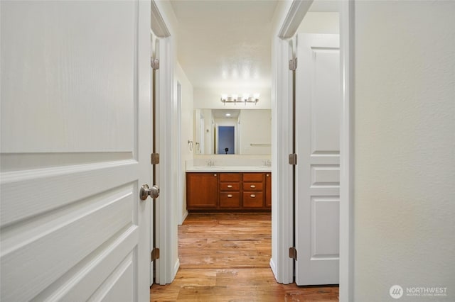 corridor with a sink and light wood-style flooring