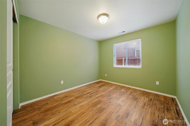 empty room with baseboards and wood finished floors