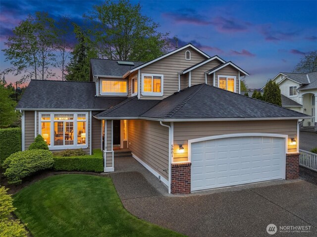 traditional home featuring a garage, driveway, a shingled roof, and solar panels