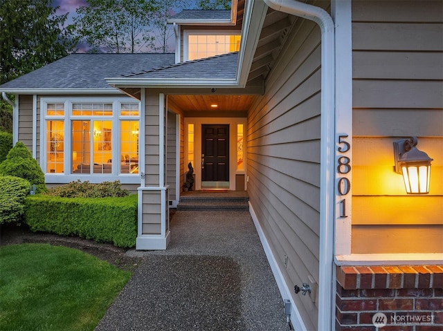 view of exterior entry with a shingled roof