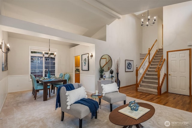 living room featuring a chandelier, beamed ceiling, stairs, high vaulted ceiling, and light wood finished floors