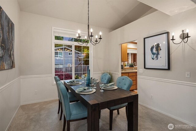 dining room featuring a chandelier, light carpet, lofted ceiling, and baseboards