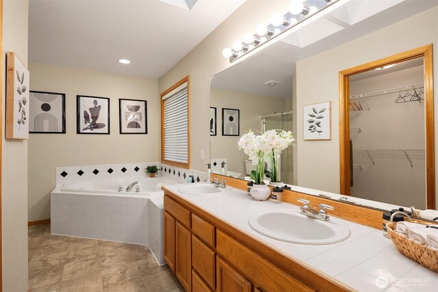 bathroom with a garden tub, a shower stall, double vanity, and a spacious closet