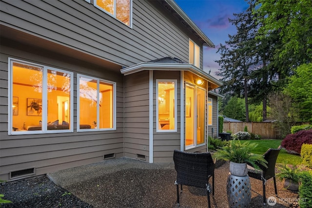 property exterior at dusk featuring crawl space, fence, and a patio area