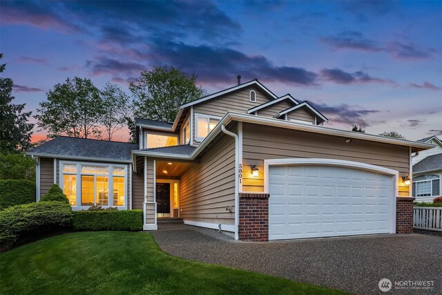 view of front of house with an attached garage, brick siding, driveway, and a yard