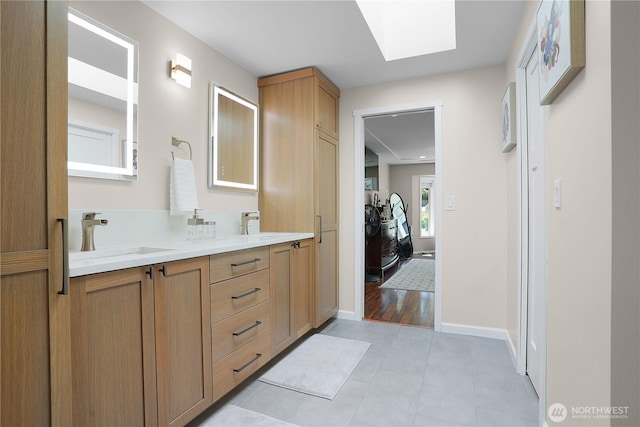 1120 Maple Valley Rd SW, Olympia, WA 98512 - bathroom featuring a skylight, double vanity, tile patterned flooring, and baseboards
