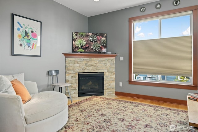 living area with wood finished floors, plenty of natural light, a fireplace, and baseboards