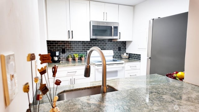 kitchen featuring stainless steel appliances, tasteful backsplash, and white cabinets