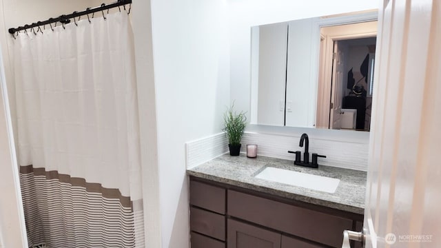 full bath with decorative backsplash, vanity, and curtained shower