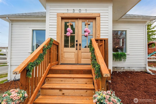 view of exterior entry with a shingled roof and french doors