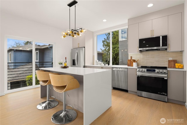 1911C N 120th St, Seattle, WA 98133 - kitchen with stainless steel appliances, light wood-style flooring, a kitchen island, light countertops, and recessed lighting
