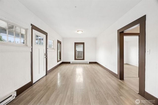 entrance foyer with a baseboard radiator, light wood-type flooring, and baseboards