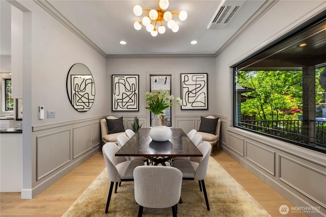 3018 22nd Ave W, Seattle, WA 98199 - dining area with plenty of natural light, a decorative wall, a chandelier, light wood-style floors, and crown molding