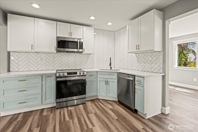 821 15th St, Bremerton, WA 98337 - kitchen featuring stainless steel appliances, light countertops, white cabinetry, wood finished floors, and tasteful backsplash