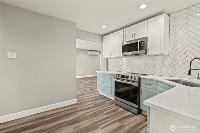 821 15th St, Bremerton, WA 98337 - kitchen featuring appliances with stainless steel finishes, a wall mounted air conditioner, decorative backsplash, white cabinets, and light countertops