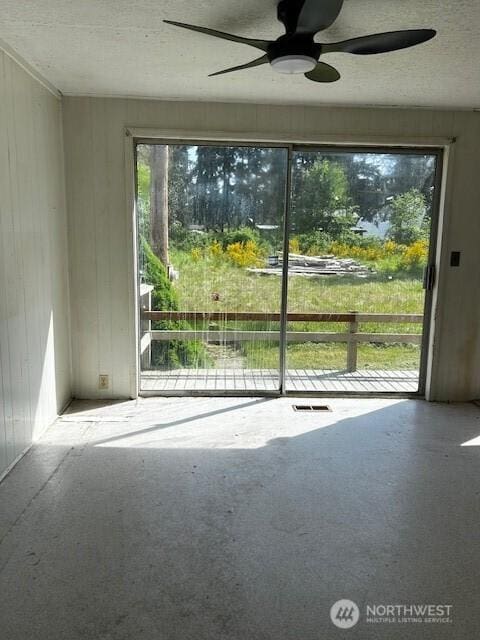 unfurnished room with carpet flooring, a textured ceiling, ceiling fan, and wood walls