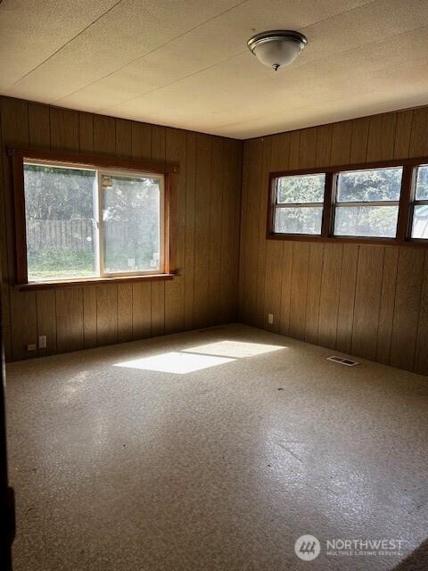 carpeted spare room with wood walls