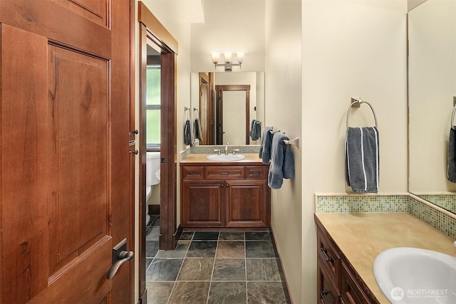 1624 Mallard Ln, Bellevue, WA 98008 - bathroom featuring two vanities, stone finish flooring, toilet, and tasteful backsplash