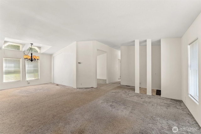 unfurnished living room featuring a chandelier and carpet