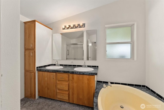 bathroom with double vanity, a stall shower, and a bath