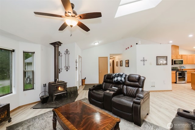 760 Lewis Rd W, Seabeck, WA 98380 - living area with light wood-style floors, a wood stove, vaulted ceiling, a skylight, and ceiling fan