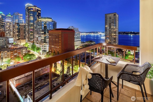 balcony at twilight with a view of city lights and a water view