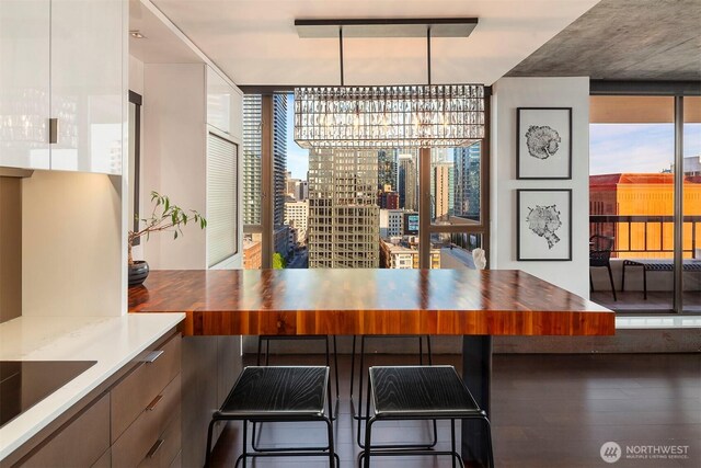 dining area with expansive windows, a chandelier, plenty of natural light, and wood finished floors