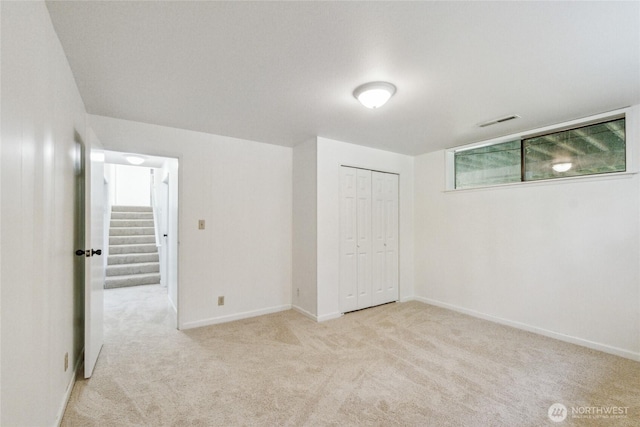 unfurnished bedroom featuring light carpet, baseboards, and a closet