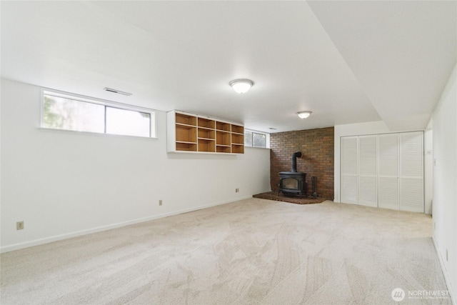 basement with a wood stove, carpet flooring, and baseboards