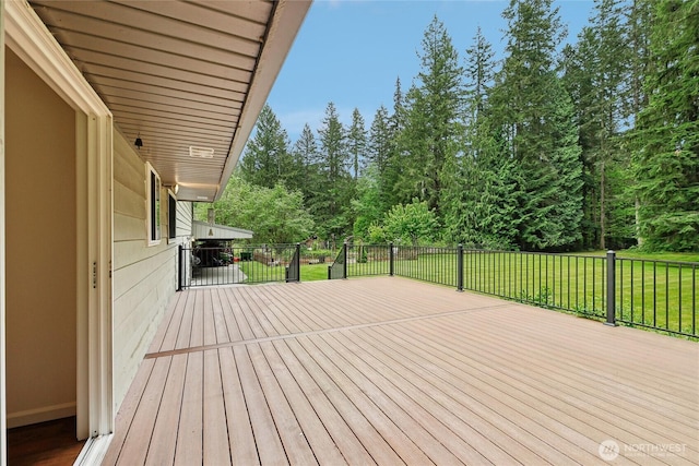 wooden deck featuring a lawn and view of wooded area