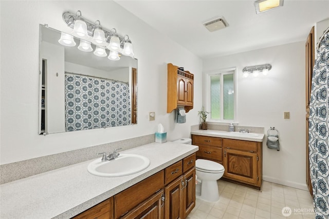 full bathroom with toilet, two vanities, and tile patterned flooring