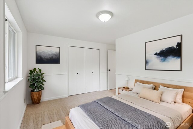 bedroom with light colored carpet, a closet, baseboards, and multiple windows