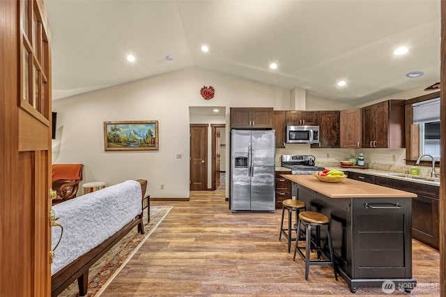 7468 Glacier Springs Dr, Deming, WA 98244 - kitchen with appliances with stainless steel finishes, a sink, lofted ceiling, a breakfast bar area, and light countertops