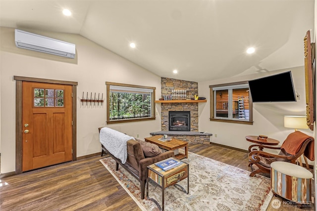 7468 Glacier Springs Dr, Deming, WA 98244 - living area with a wall unit AC, vaulted ceiling, wood finished floors, baseboards, and a stone fireplace
