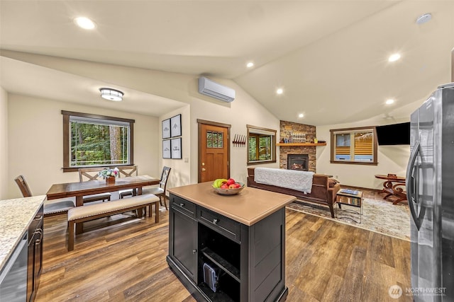 7468 Glacier Springs Dr, Deming, WA 98244 - kitchen with freestanding refrigerator, a wall mounted air conditioner, light countertops, dark cabinets, and a fireplace